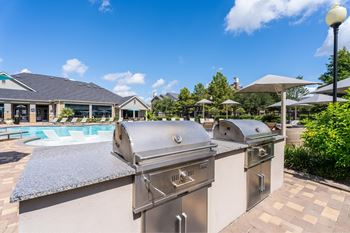 A row of stainless steel grills are lined up on a patio.